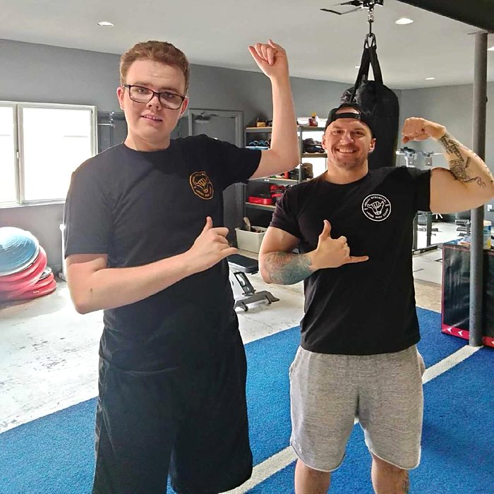 Brayden and Coach Dave in Shaka shirts, flexing and throwing the shaka sign